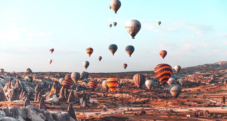 Heißluftballons im Flug über eine felsige Landschaft.