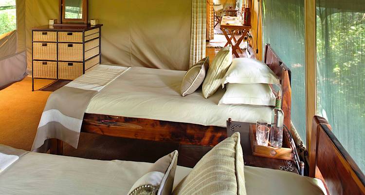 Intérieur d'une tente avec un lit et des meubles en bois.