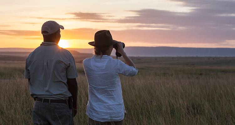 Deux personnes regardant le coucher de soleil dans la savane.