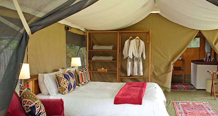 Intérieur de tente avec lit et coussins décoratifs.