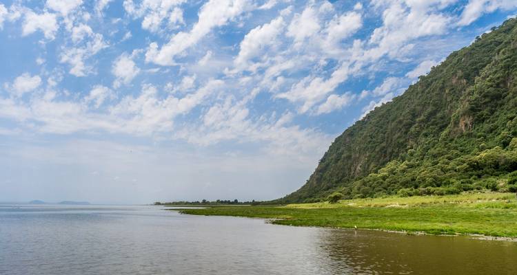 Ruhiger See mit steilen Berghängen unter blauem Himmel.