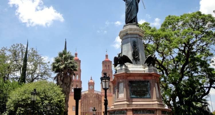 A statue with twin church towers in the background.