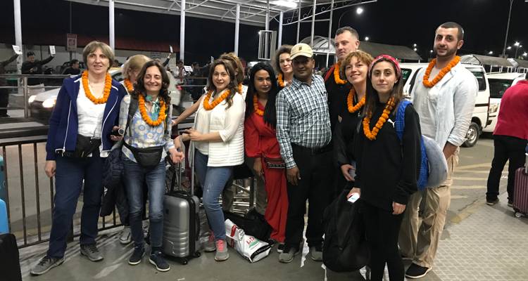 Gruppe von Touristen mit Ringelblumengirlanden an einem Verkehrsknotenpunkt im Freien bei Nacht.
