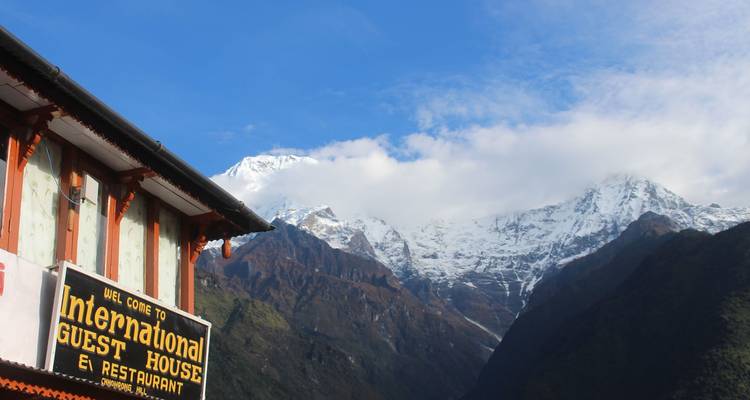 Un panneau de maison d'hôtes avec des montagnes enneigées en arrière-plan.