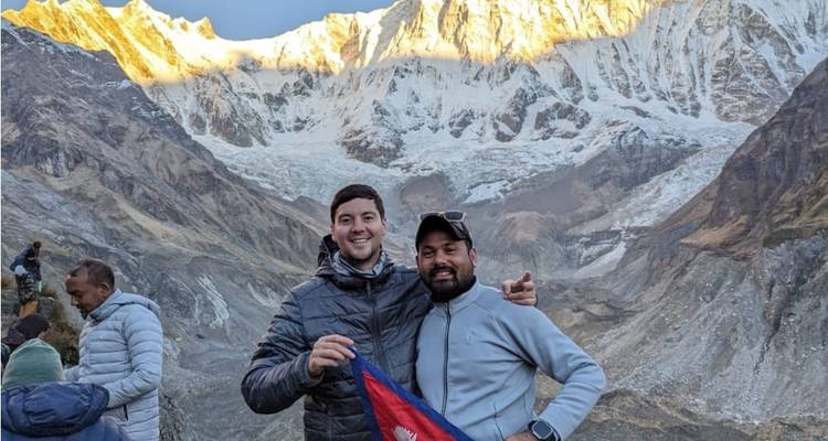Deux hommes posant devant des montagnes enneigées au crépuscule.