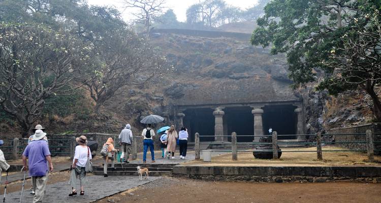 Des touristes s'approchant de l'entrée d'une grotte historique.