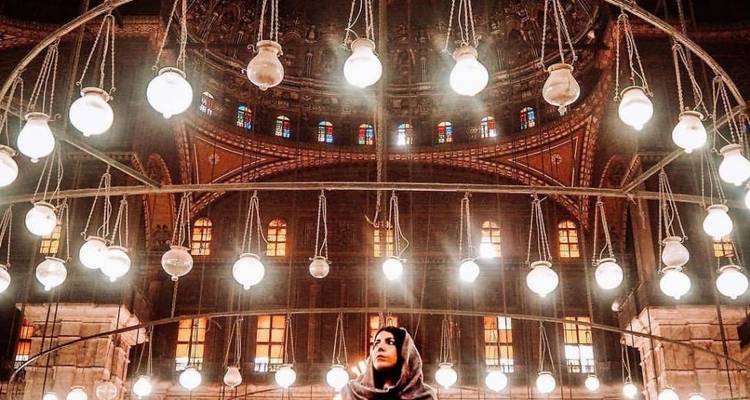 Innenansicht einer Moschee mit von der Decke hängenden Lampen.