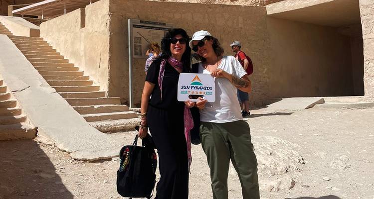 Deux femmes posant avec un panneau sur un site antique.