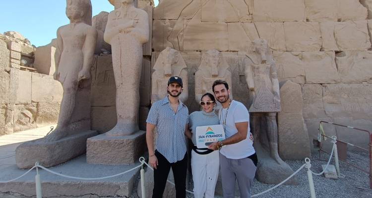 Gruppe von Touristen, die mit einem Schild vor großen Statuen posieren.