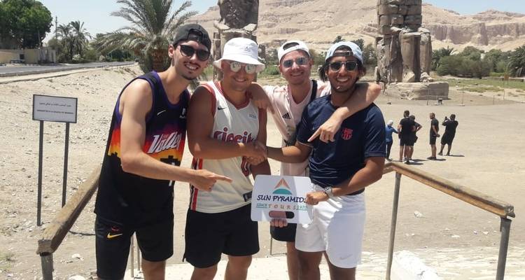 Junge Touristen, die vor antiken Statuen mit einem Schild posieren.