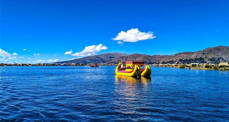 Gele rietboot drijvend op het Titicacameer onder een heldere blauwe lucht.
