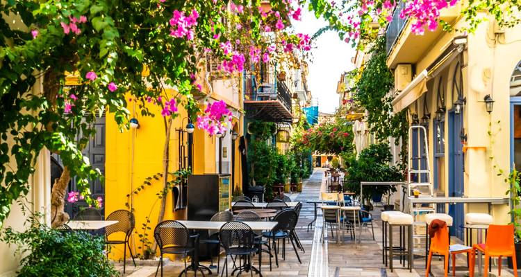Ruelle pittoresque avec des fleurs éclatantes et des tables de café.