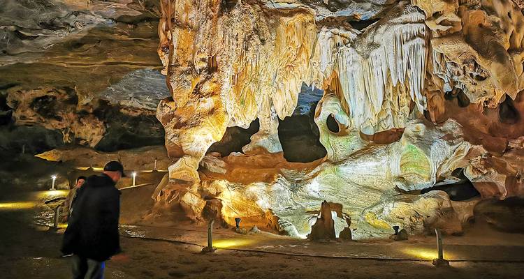 Grottinterieur met stalactieten en mensen die het gebied verkennen.