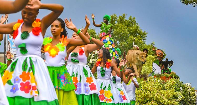 Parade met mensen in kleurrijke kostuums en leeuwenbeeld.