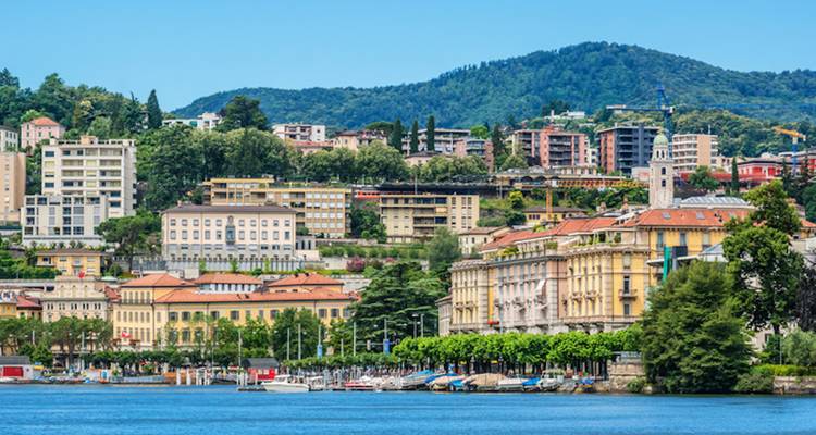 Cityscape with colorful buildings and hills in the background beside a lake.