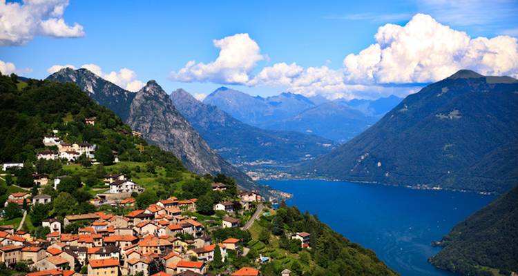 Scenic view of a lake surrounded by mountains and villages.