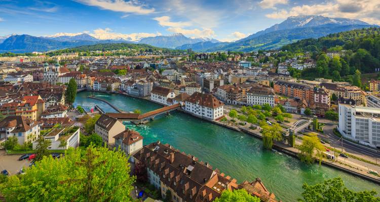 Scenic cityscape with a river running through, surrounded by mountains.