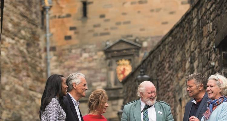 Groep mensen die voor een historische kasteelmuur staan.