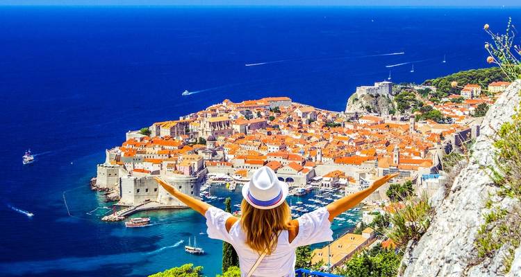 Woman with arms spread overlooking a coastal city.