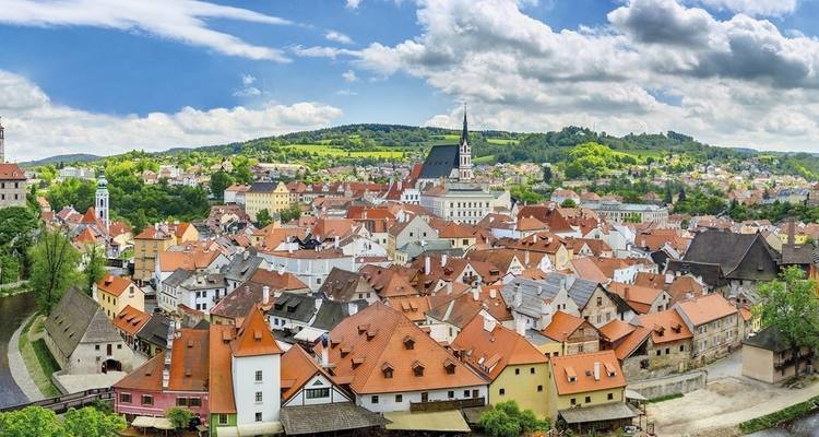 Uitzicht over de roodgedakte gebouwen van Cesky Krumlov, omringd door weelderig groen.