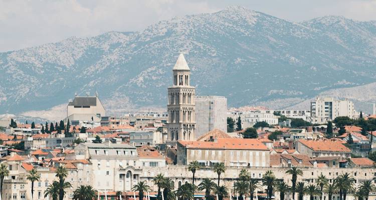 A cityscape view of Split, Croatia, with a prominent bell tower against mountains.