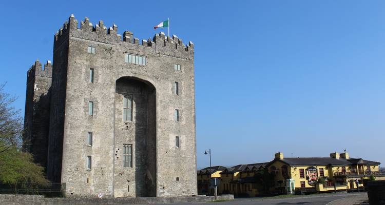Stone castle with a national flag atop against a clear blue sky.