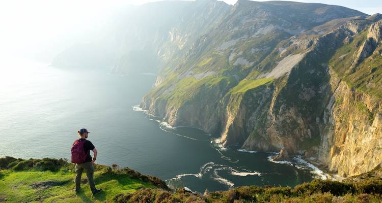 Hiker looking towards dramatic seaside cliffs.