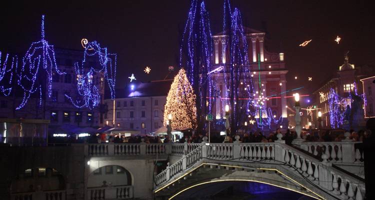 Nächtliche Stadtlandschaft mit festlichen Lichtern und einer geschmückten Brücke.