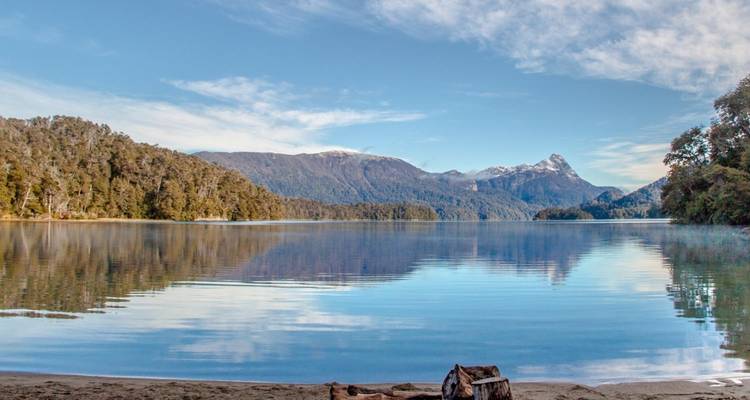 Een rustig meer dat bergen en wolken weerkaatst.