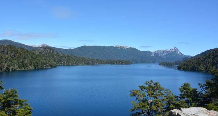 Een wijd uitzicht op een meer omringd door beboste bergen.