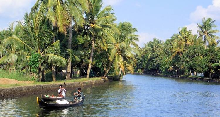 Two men paddling a small boat along a lush waterway.