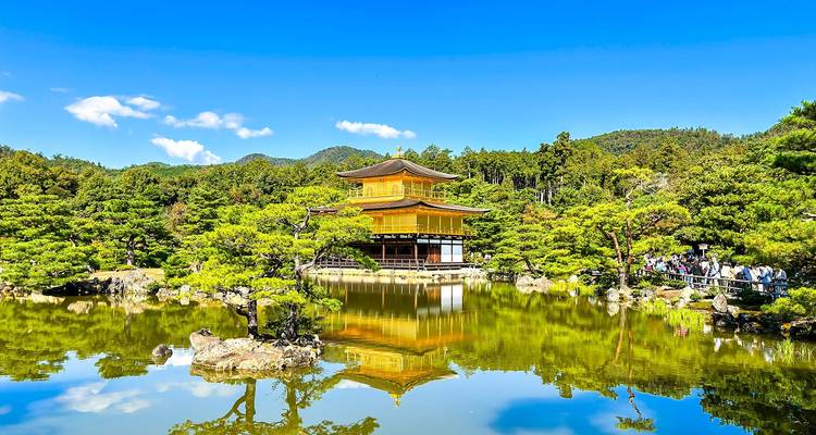 Goldener Pavillon spiegelt sich im Wasser wider, umgeben von Bäumen