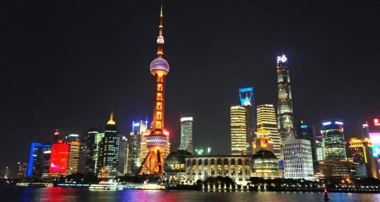 Horizon de Shanghai illuminé la nuit avec des gratte-ciel se reflétant dans l'eau.