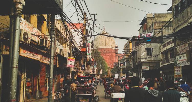 Busy street with various people and a dome structure in the background.