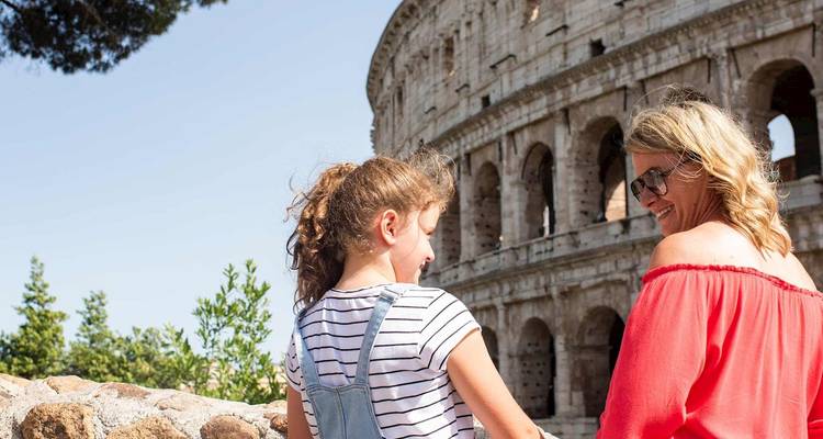 Mother and daughter smile together with the Colosseum arches rising behind them.