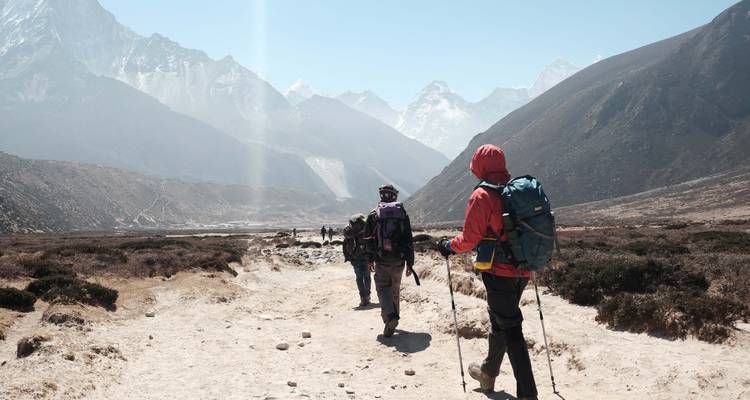 Des randonneurs marchant vers de majestueuses montagnes sous un ciel dégagé.