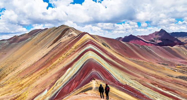 Colorful striped mountains with two people hiking.