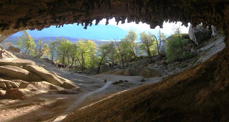 Entrée de grotte avec des touristes et une forêt luxuriante au-delà.