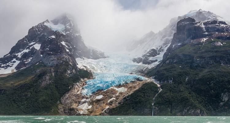 Un glacier de montagne s'écoulant le long de pentes rocheuses.