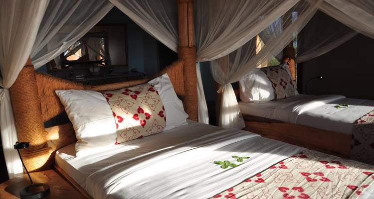 Ein Doppelbett unter Moskitonetzen in einem Lodge-Zimmer.