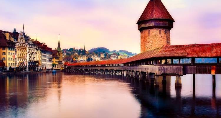 Pont en bois historique enjambant une rivière dans un cadre urbain.