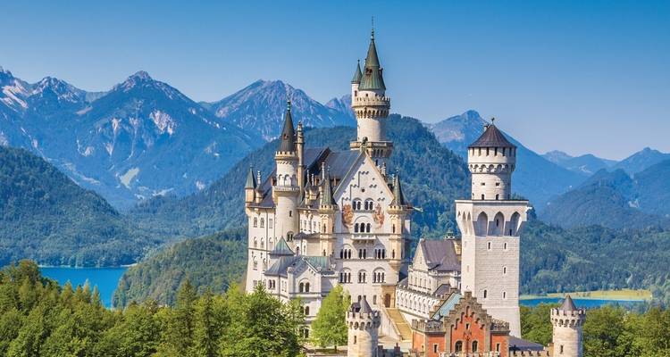 Schloss Neuschwanstein mit Bergen im Hintergrund und Wald.