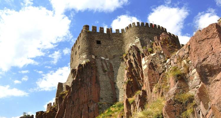 Oude stenen kasteelstructuur op rotsachtig terrein.