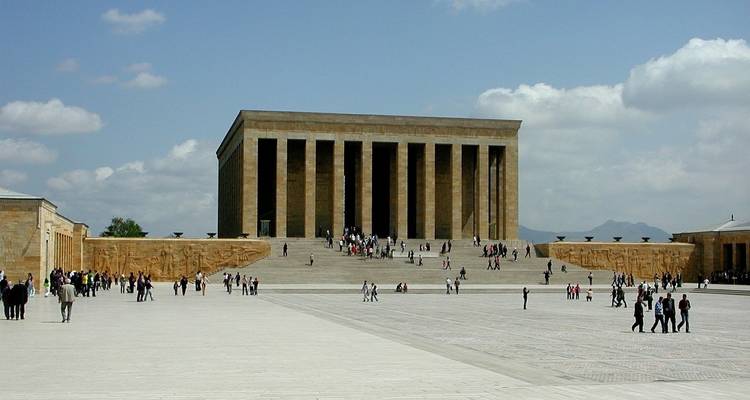 Groot plein met een monumentaal gebouw en veel bezoekers.