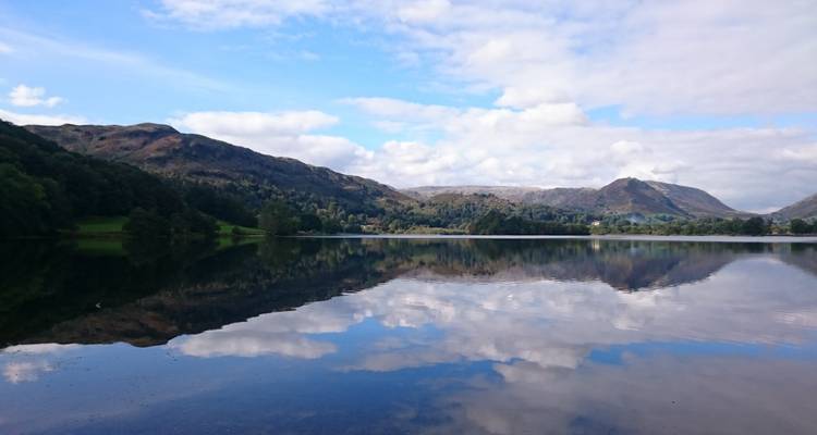 Weerspiegeling van bergen en lucht in een meer.