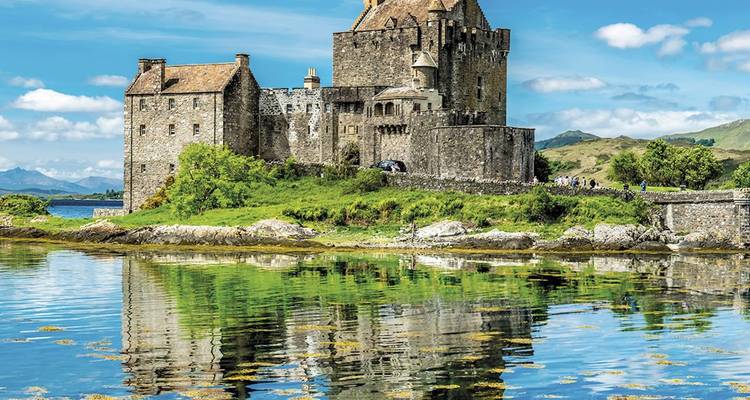 Reflet du château médiéval d'Eilean Donan sur un loch calme entouré de hautes terres verdoyantes.