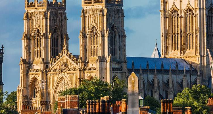 Fachada detallada de las torres góticas gemelas de York Minster iluminadas por la cálida luz del atardecer.