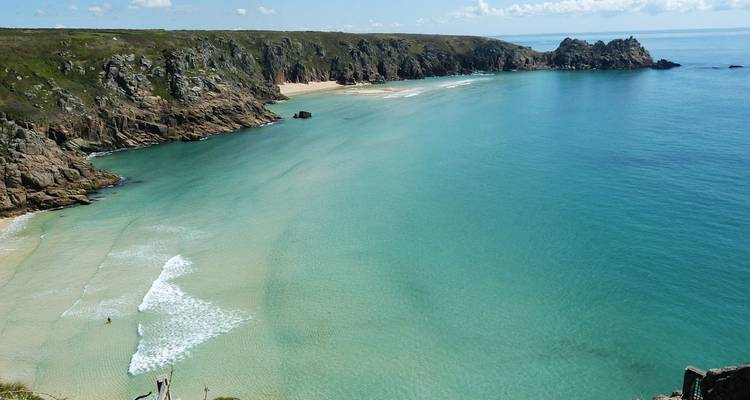 Pristine beach with clear turquoise water and steep cliffs.
