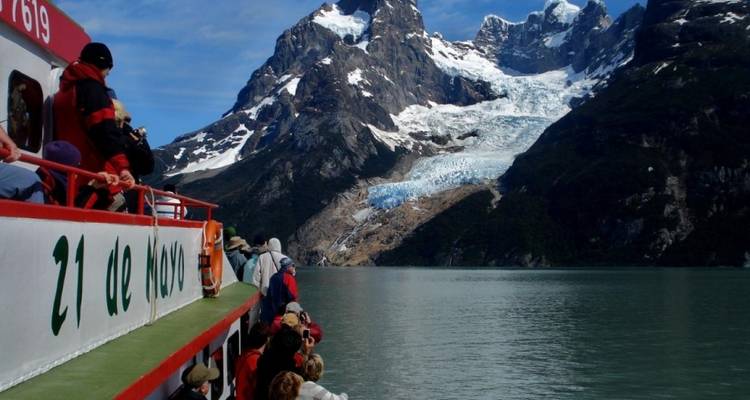 Menschen auf einem Boot beobachten einen Gletscher in den Bergen.