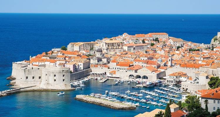 Luftaufnahme von Dubrovniks Altstadt und Hafen mit dem Meer und den Festungsmauern.